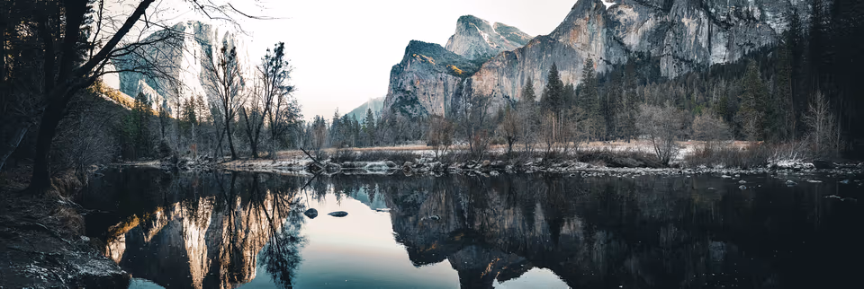 Yosemite cliffs and winter trees reflected in still valley water