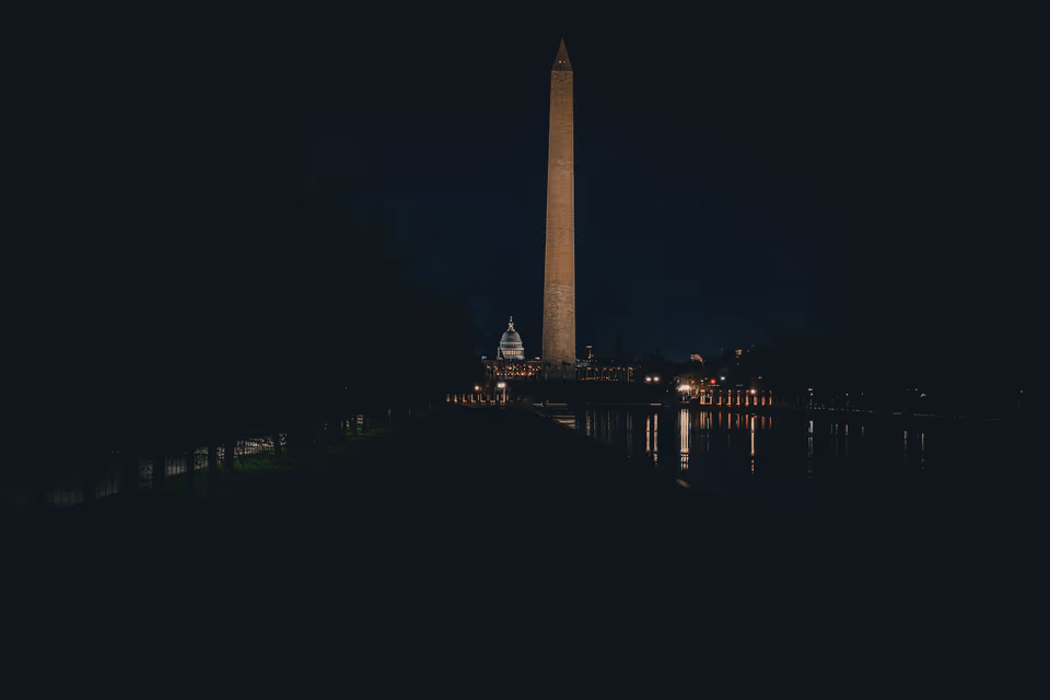 The Washington Monument illuminated at blue hour with a dark reflecting pool