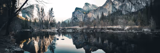 Yosemite cliffs and winter trees reflected in still valley water